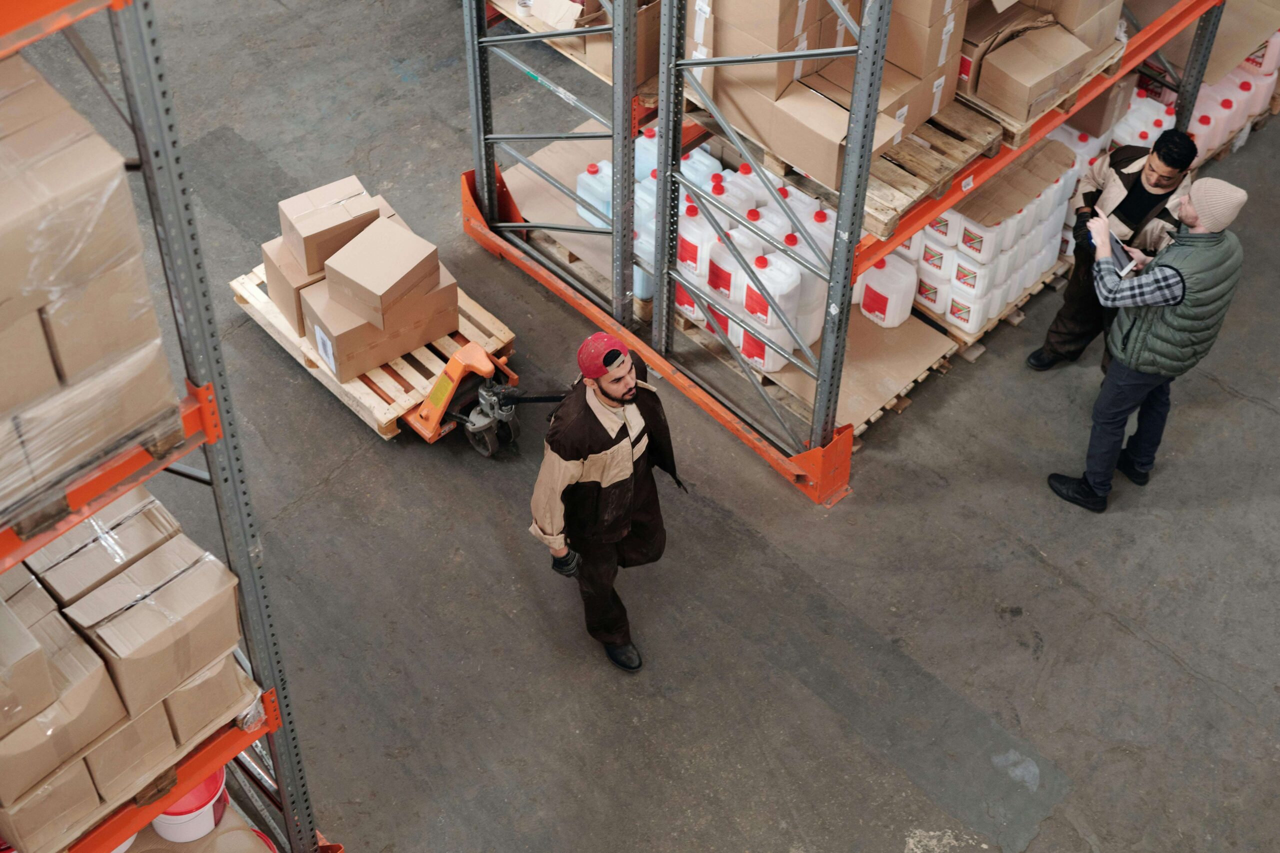 Three men working in a warehouse with racks for of packaged boxes