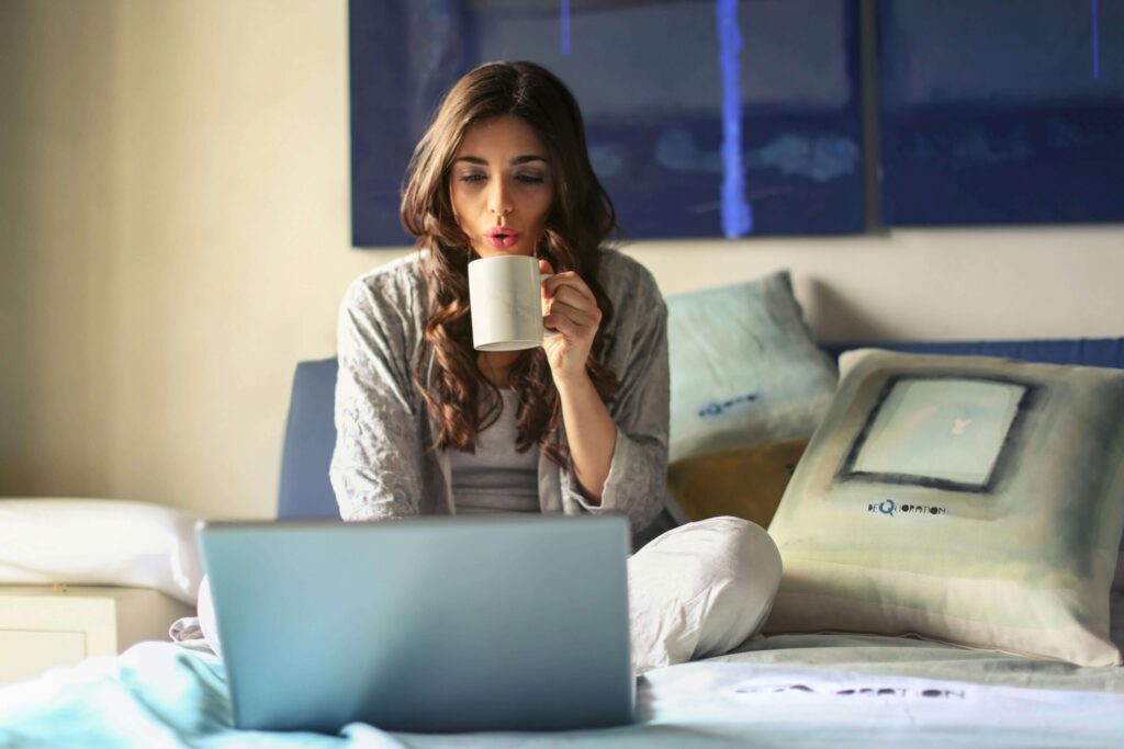An online seller working in her bedroom while sipping coffee