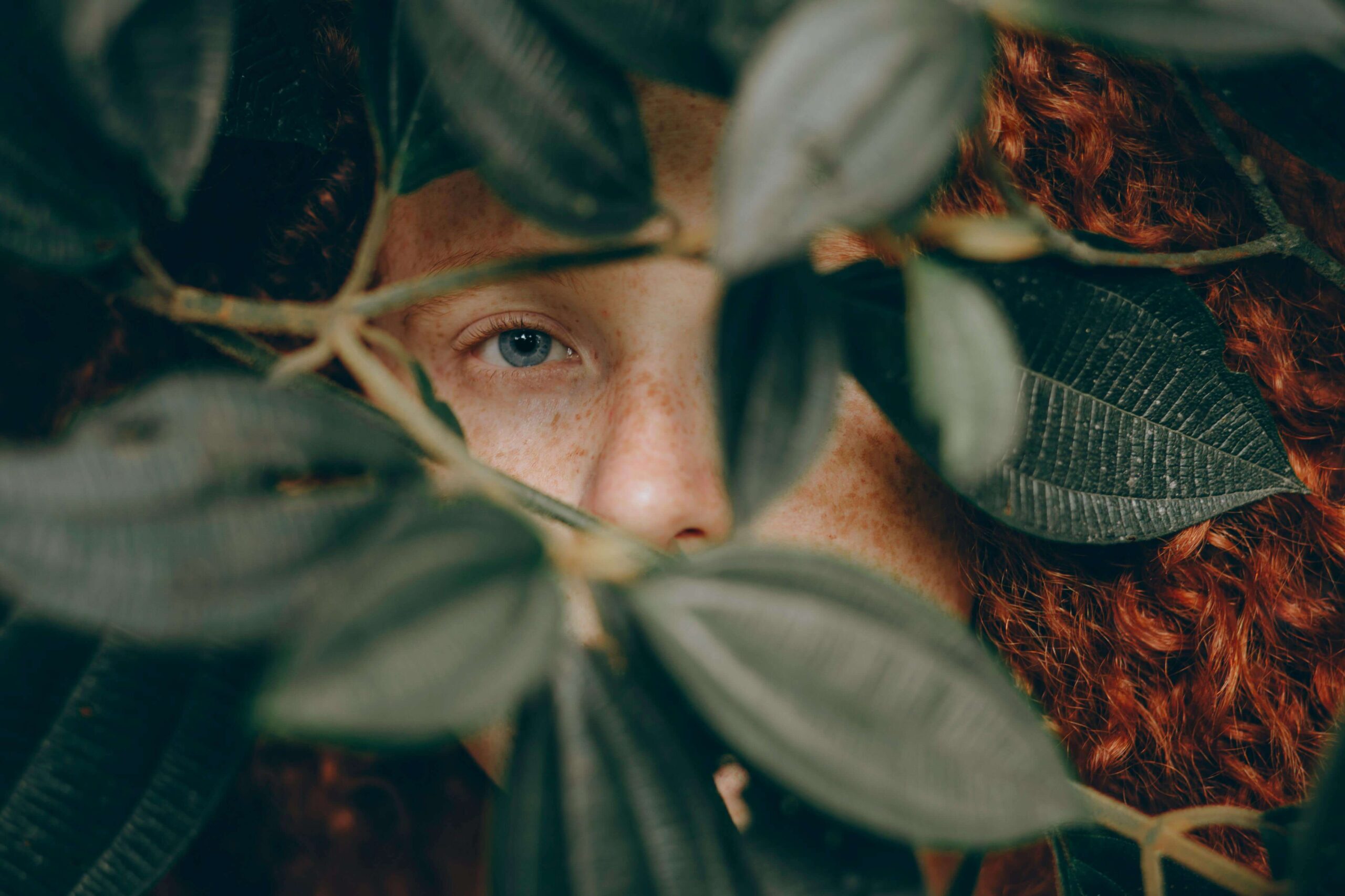girl hiding behind leaves