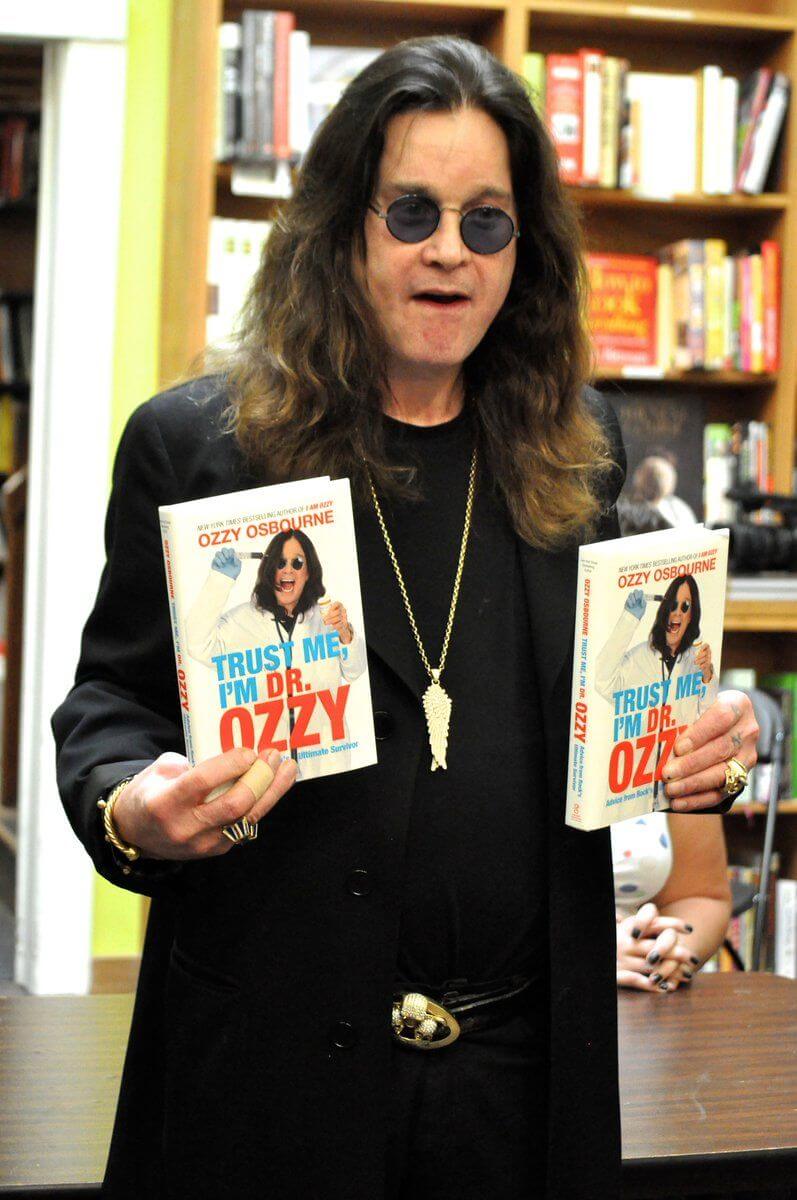 Ozzy Osbourne holding copies of the book Trust Me, I’m Dr. Ozzy