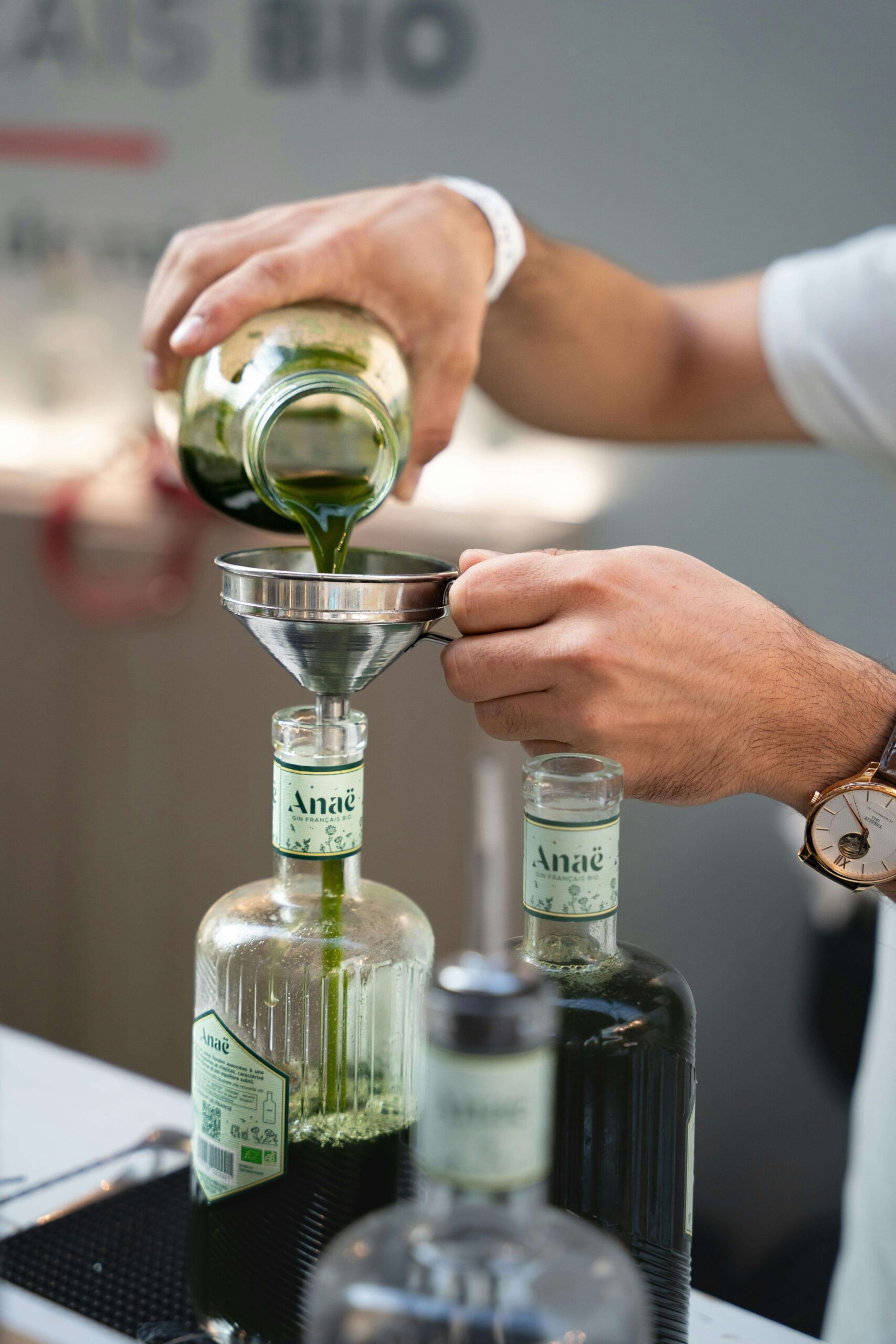 man pouring green fluid into a bottle through a funnel