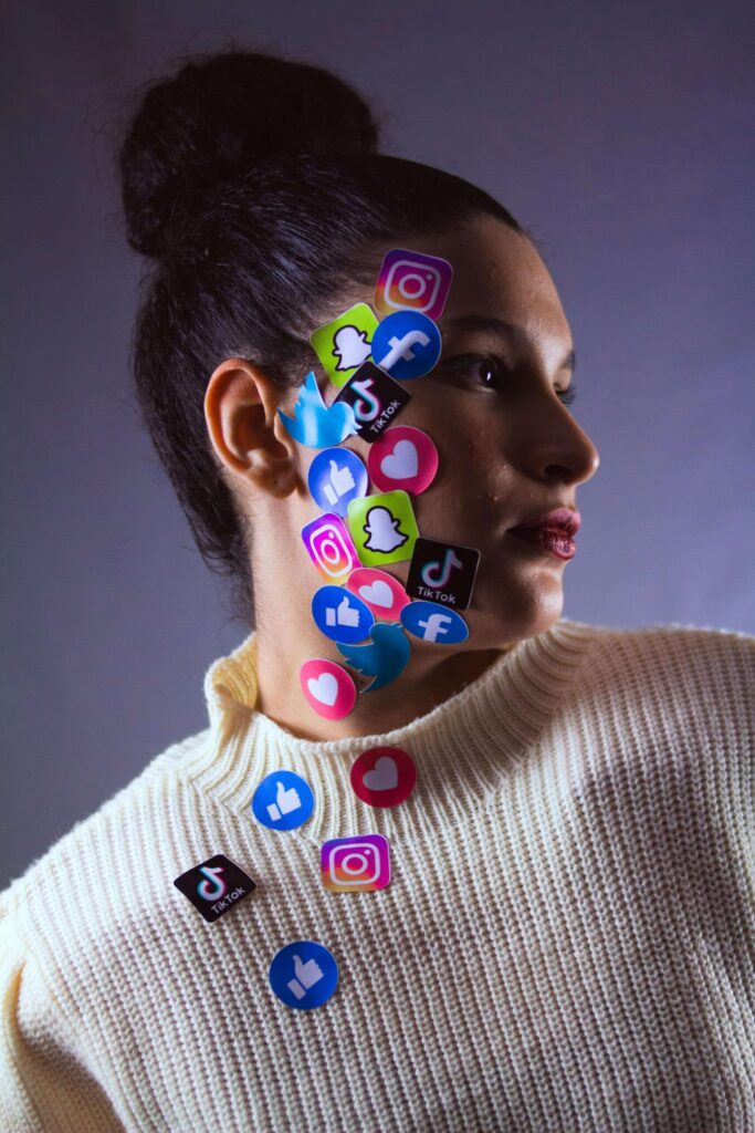 woman with stickers of social media site logos stuck on her face
