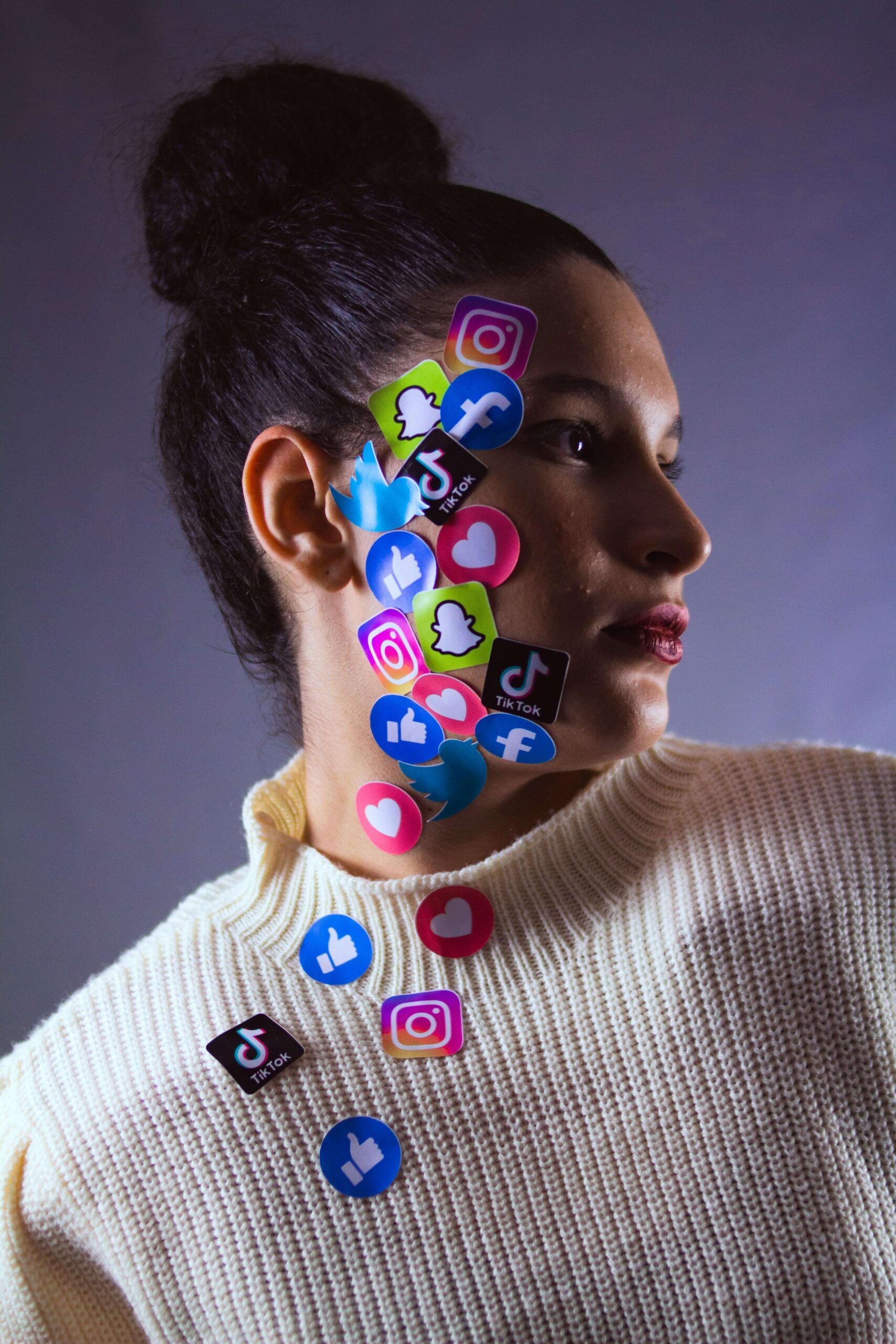 woman with stickers of social media site logos stuck on her face